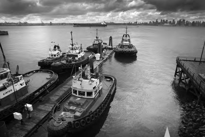 Cates tugboat fleet at the Lower Lonsdale waterfront, Burrard Inlet — Vancouver skyline in the distance